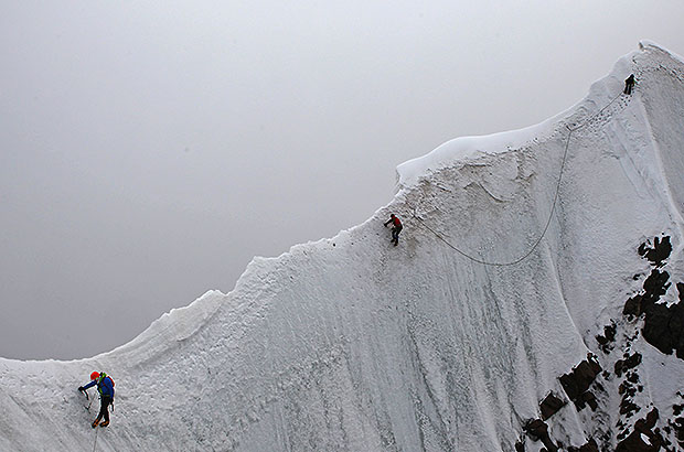 Passing a difficult section of the snow ridge, climbing Mount Ushba