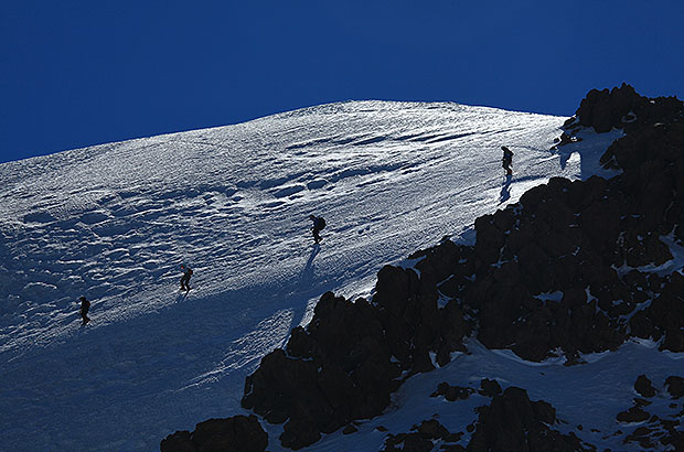 A group of climbers descends from the summit of Mount Kazbek. Caucasus, Georgia.