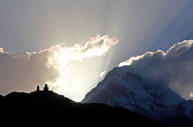 Summit of Mount Kazbek and Gergeti monastery at sunset