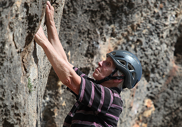80ти летняя скалолазка штурмует отвесную скалу на острове Майорка, Испания