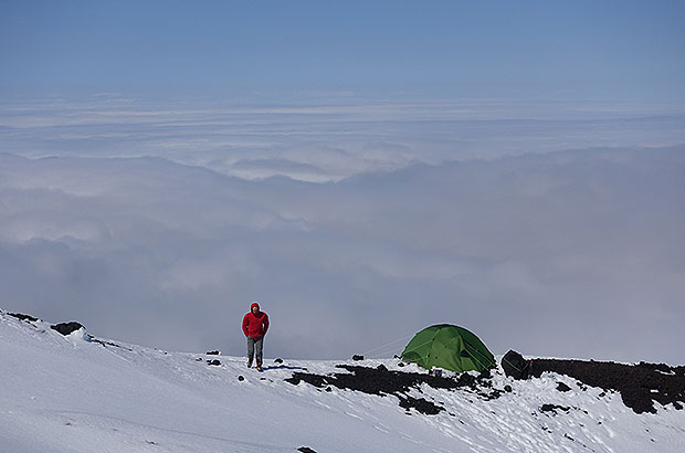 The slopes of the dome of Klyuchevskaya Sopka and our camp above the clouds. Below - the selva of the Kamchatka River