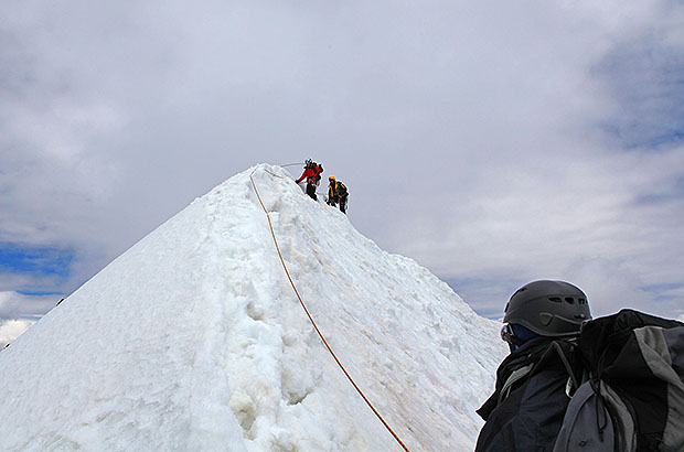 Climbing the snow dome of Mount Ushba, belay organized over the snow ridge